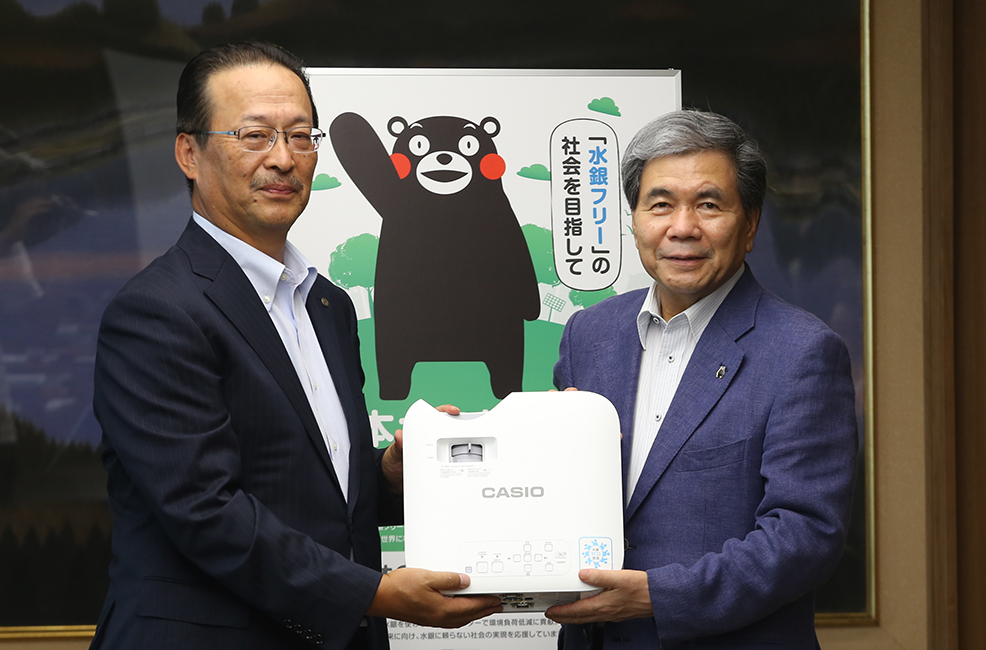 「水銀フリー」社会を目指す熊本県の活動に賛同し、2018年8月7日、熊本県庁県知事室にて、蒲島郁夫熊本県知事ご出席のもとカシオの水銀ゼロのプロジェクターの贈呈式を行いました。